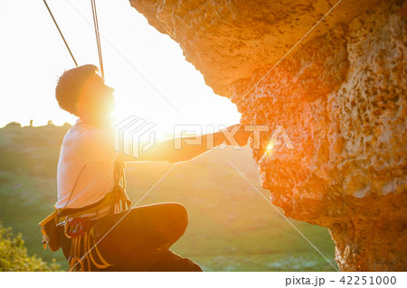 Picture of man clambering over rock. 42251000