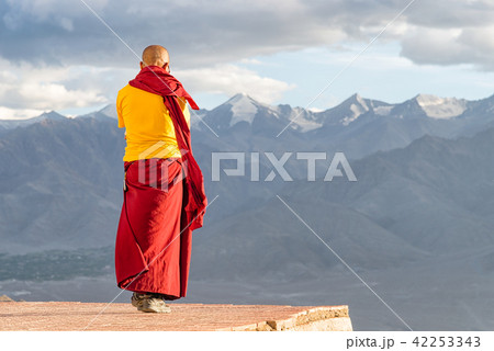 Indian tibetan monk standing in front of mountains Indian tibetan monk standing in front of mountains 42253343