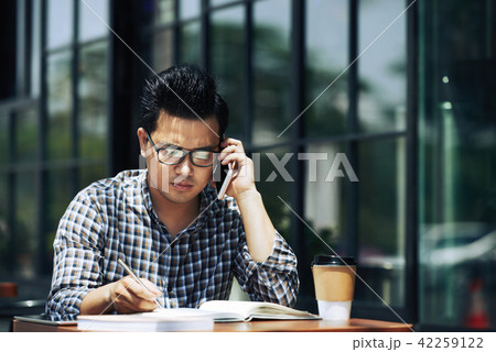 Young entrepreneur working at table in cafe 42259122