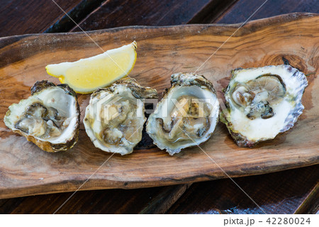 Oysters with lemon on wooden plate. 42280024