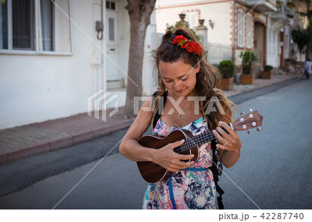 Smiling woman with roses in hairstyle holds in hands musical instrument Smiling woman with roses in hairstyle holds in hands musical instrument 42287740