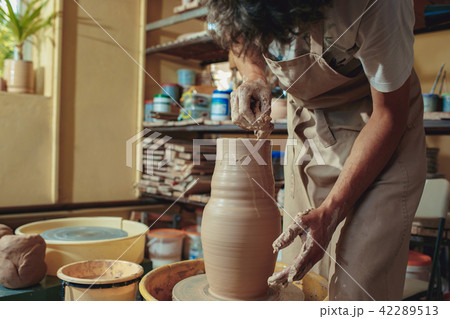 Creating a jar or vase of white clay close-up. Master crock. Man hands making clay jug macro. Creating a jar or vase of white clay close-up. Master crock. Man hands making clay jug macro. 42289513