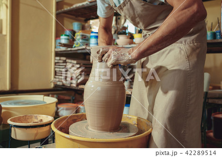 Creating a jar or vase of white clay close-up. Master crock. Man hands making clay jug macro. Creating a jar or vase of white clay close-up. Master crock. Man hands making clay jug macro. 42289514