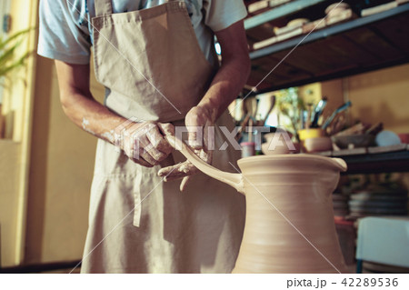 Creating a jar or vase of white clay close-up. Master crock. Man hands making clay jug macro. Creating a jar or vase of white clay close-up. Master crock. Man hands making clay jug macro. 42289536