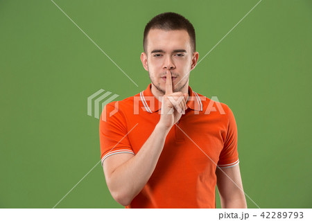 The young man whispering a secret behind her hand over green background The young man whispering a secret behind her hand over green background 42289793