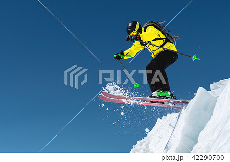 A skier in full sports equipment jumps into the precipice from the top of the glacier against the A skier in full sports equipment jumps into the precipice from the top of the glacier against the 42290700