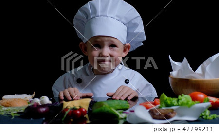 Little boy is cooking at the kitchen, he is wearing chefs suit 42299211