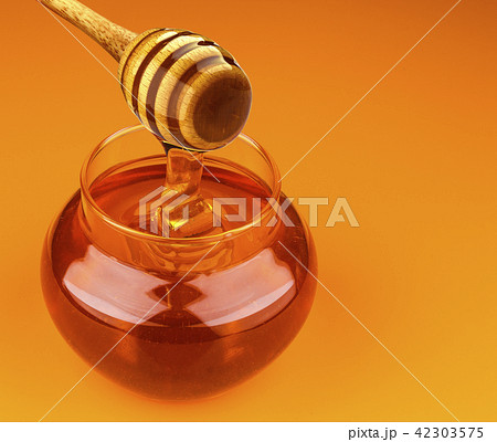 Honey stick and bowl of pouring honey isolated on yellow background 42303575