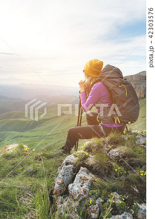 Smiling girl traveler in a yellow hat and a pair of sunglasses ssitting at the foot of epic rocks Smiling girl traveler in a yellow hat and a pair of sunglasses ssitting at the foot of epic rocks 42303576