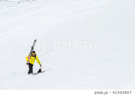 A skier in a helmet and mask with a backpack rises on a slope against the background of snow and a 42303607
