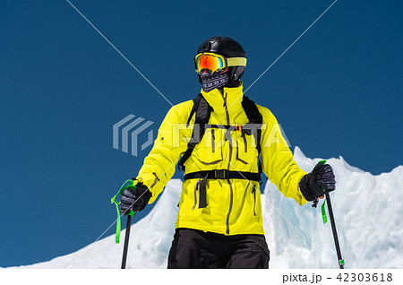 Skier standing on a slope. Man in a light suit, the helmet and mask in skiing is to ski. In the Skier standing on a slope. Man in a light suit, the helmet and mask in skiing is to ski. In the 42303618