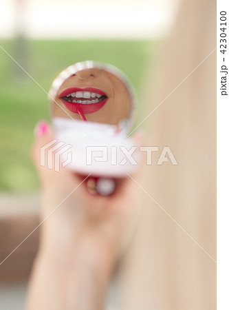Woman applying lipstick outdoors before interview 42304100