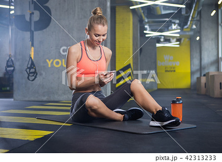 Happy woman is using smartphone during training indoors 42313233