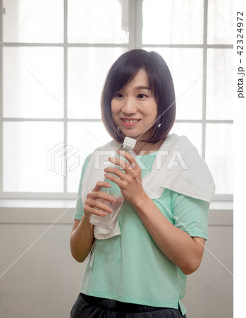 Woman drinking water after exercise Woman drinking water after exercise 42324972