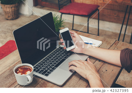 Business man holding phone and using laptop Business man holding phone and using laptop 42327395