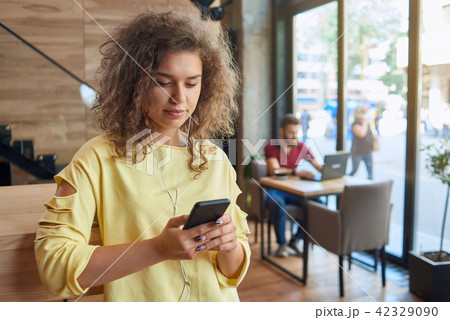 Front view of curly student wearing yellow blouse listening to music. Front view of curly student wearing yellow blouse listening to music. 42329090