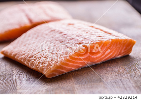 Close-up raw salmon fillets on wooden table Close-up raw salmon fillets on wooden table 42329214