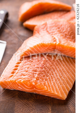 Close-up raw salmon fillets on wooden table Close-up raw salmon fillets on wooden table 42329216
