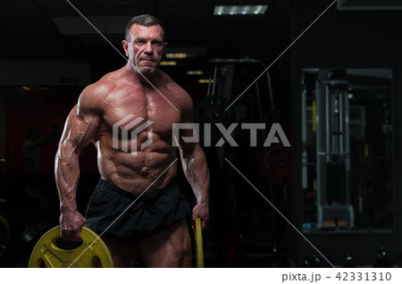 Strong mature man with relief body posing in gym Strong mature man with relief body posing in gym 42331310