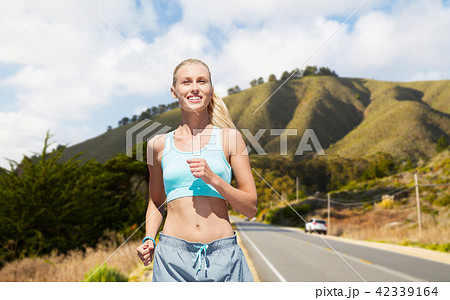 happy woman running nearby road over big sur hills 42339164