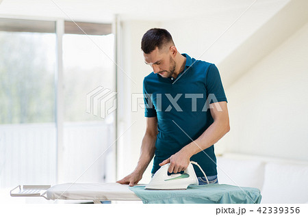 man ironing shirt by iron at home 42339356