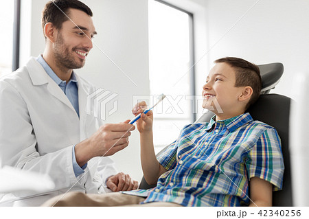 dentist giving toothbrush to kid patient at clinic dentist giving toothbrush to kid patient at clinic 42340256