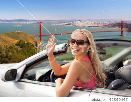 happy young woman in convertible car waving hand happy young woman in convertible car waving hand 42340447