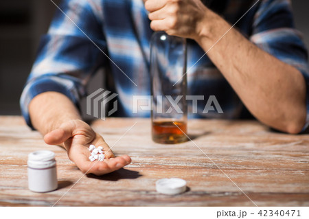 unhappy drunk man with bottle of alcohol and pills unhappy drunk man with bottle of alcohol and pills 42340471