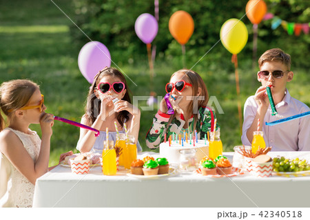 happy kids blowing party horns at summer birthday 42340518