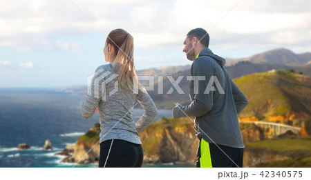 couple with earphones running over big sur coast couple with earphones running over big sur coast 42340575