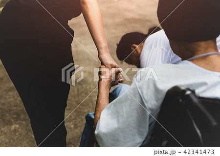 Caretaker and daughter with patient in wheelchair  42341473