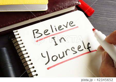 Man is writing Believe In Yourself in a note. 42345652