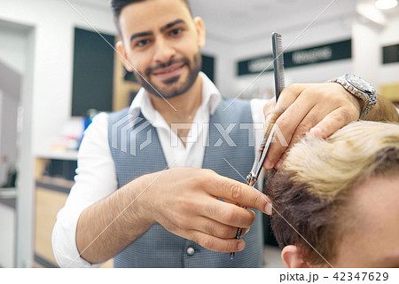 Doing new hairstyle for male model using sharp metallic scissors. Doing new hairstyle for male model using sharp metallic scissors. 42347629