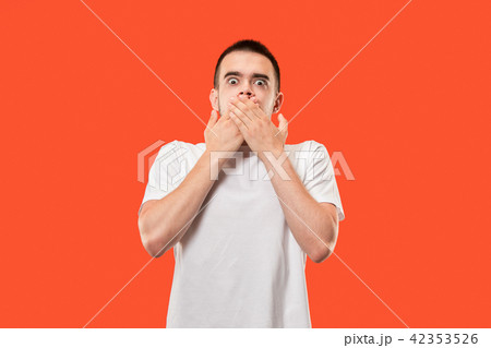 The young man whispering a secret behind her hand over orange background 42353526