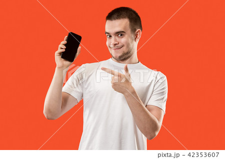 The happy man showing at empty screen of mobile phone against orange background. 42353607
