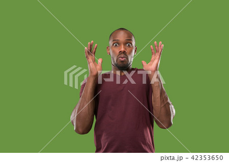 The young attractive man looking suprised isolated on green 42353650