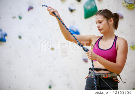 Close-up photo of girl climber with safety rope in hands at sports hall Close-up photo of girl climber with safety rope in hands at sports hall 42355256