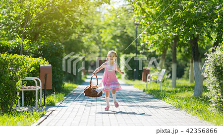 The girl runs along the road with a basket of bread. The girl runs along the road with a basket of bread. 42356866
