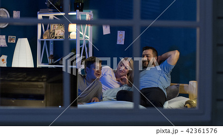 Relaxing family watching TV on bed together Relaxing family watching TV on bed together 42361576