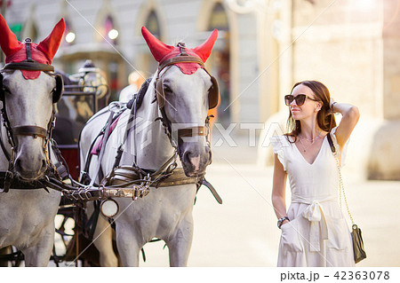 Tourist girl enjoying a stroll through Vienna and looking at the beautiful horses in the carriage Tourist girl enjoying a stroll through Vienna and looking at the beautiful horses in the carriage 42363078