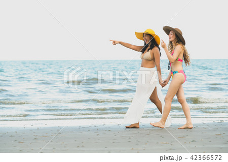 Happy women go sunbathing at sand beach in summer. Happy women go sunbathing at sand beach in summer. 42366572