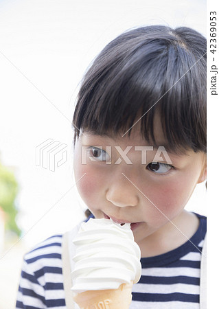 遊園地でソフトクリームを食べる女の子の写真素材
