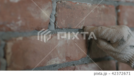 closeup of worker forming seam between bricks 42372671