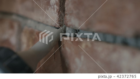 closeup of worker filling seam between bricks with mortar from sealant gun 42372765