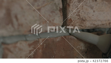 closeup of worker filling seam between bricks with mortar from sealant gun 42372766
