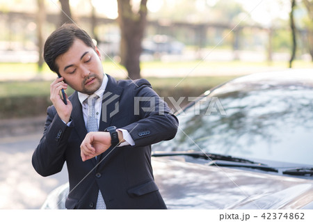 Handsome businessman looking at watch near a car 42374862