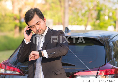 Businessman using a mobile phone near his car 42374867
