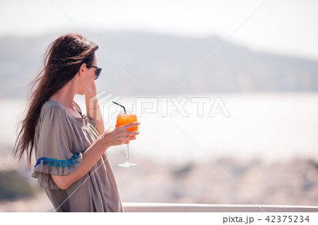 Young happy woman in outdoor cafe with tasty drink. Young happy woman in outdoor cafe with tasty drink. 42375234
