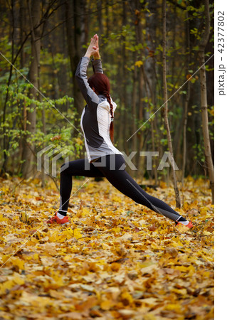 Autumn photo of sporty girl stretching in forest at morning against background of trees 42377802