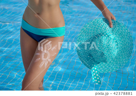 Sunscreen and beautiful female legs in the pool with a picture of the sun on his leg, conceptual Sunscreen and beautiful female legs in the pool with a picture of the sun on his leg, conceptual 42378881
